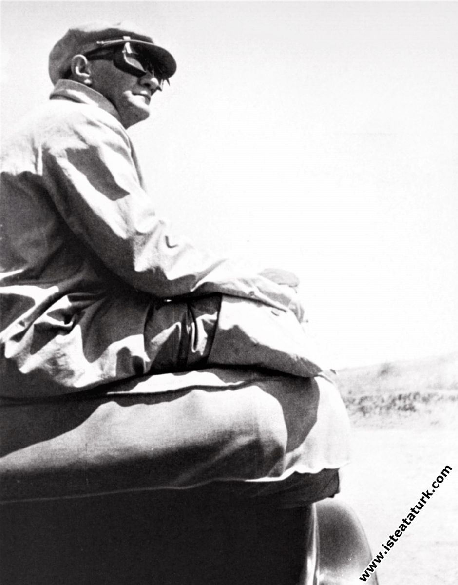 Mustafa Kemal Atatürk Çorlu Çerkezköy yakınlarında Trakya Manevralarında, arabanın üzerine bağdaş kurmuş  otururken motorlu araçların geçişini denetliyor. (17-20 Ağustos 1937)